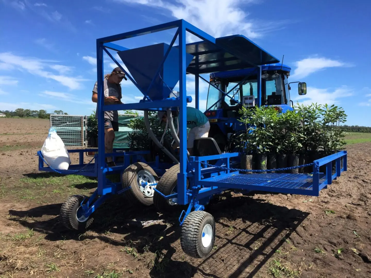 A blue tractor with a trailer attached to it.