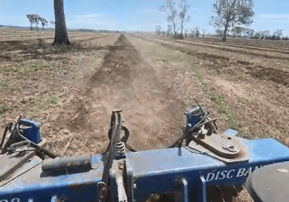 A tractor is driving down the dirt road.